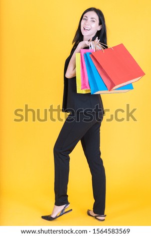 Portrait of happy businesswoman smiling in dark suit with shopping bag on yellow background using as professional modern business people and office concept.