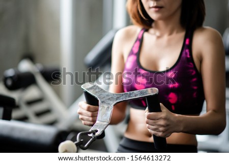 Young healthy woman working out with cable in the gym
