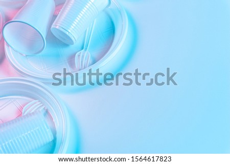 Disposable plastic tableware on a light background in pastel colors. Minimalistic ecologically clean still life. Pop Art. And ecology problem concept.