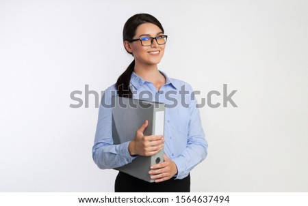 Friendly Businesswoman Holding Folder With Business Report Standing Smiling At Camera On White Studio Background. Business Accounting