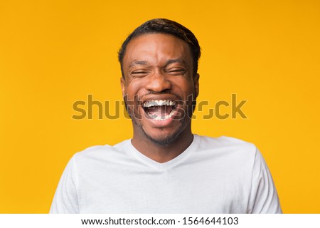 Portrait Of Laughing Black Man Standing Over Yellow Background. Sense Of Humor Concept. Studio Shot