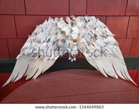 Whitewashed wooden angel wings with rustic curled bark sitting on a deep barn red table against a deep barn red wall. No property release needed this is my own original design.