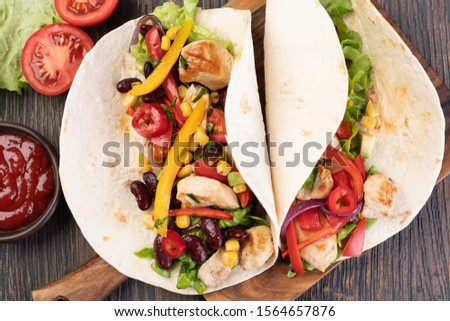 burrito with vegetables and tortilla on a wooden table