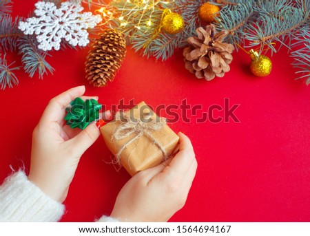 Female's hands holding  gift box with blue ribbon on red background. Christmas, New Year, Valentine's day and birthday concept.