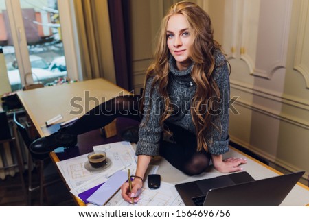 Professional interior designer or architector working with colour palette, room drawings in modern office. Young female model planning future flat or house, choosing colors and derocation. sitting on