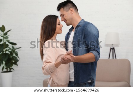 Happy couple dancing in living room at home