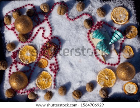 Merry Christmas and  New Year flat lay with  wooden Christmas tree, toy sled with greeting box, gold ball, walnut  and dry orange on background with snow