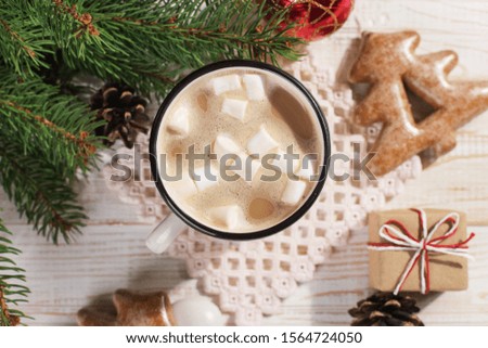 Hot Christmas drink with marshmallows in an iron mug and gingerbread cookies, on white table. New Year, holiday background, copy space.