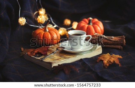 Cup of coffe on the book with cinnamon and pumpkin. Decorative cozy style