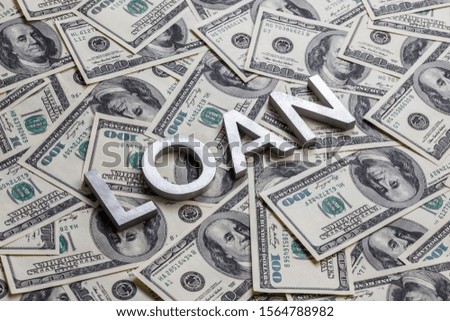 The word LOAN laid with aluminium letters on the US dollar banknotes background - with selective focus