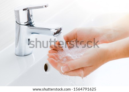Washing hands under the water tap or faucet without soap. Hygiene concept detail. Beautiful hand and water stream in bathroom. New modern basin cleaning. Royalty-Free Stock Photo #1564791625