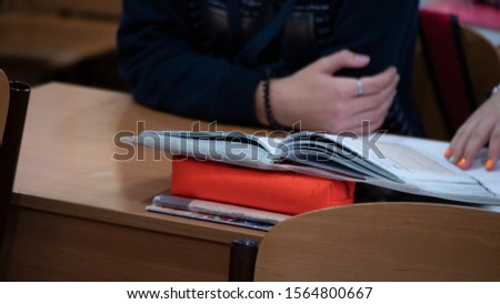 Schoolgirl in a lesson looks at a book at her desk