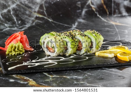 Green dragon sushi roll with salmon, cucumber and avocado. Japanese food. Traditional asian rice sushi healthy seafood. Black marble background. Horizontal photo.