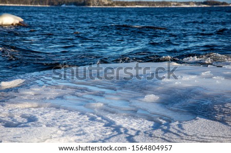 Frozen sea with snowy shores in Finland. Winter waves hitting the coast on a freezing cold sunny day. Ice and snow create unique shapes in the nature. Close-up macro photos with vibrant colors.