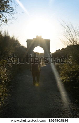 Rear view of a man walking on an old road with sun rays at sunset