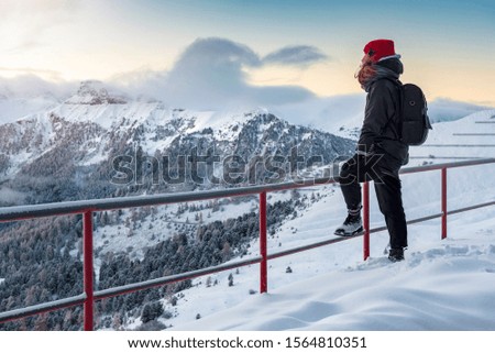 Female traveler enjoying morning over alps in italy during winter with deep snow and blue sunrise sky