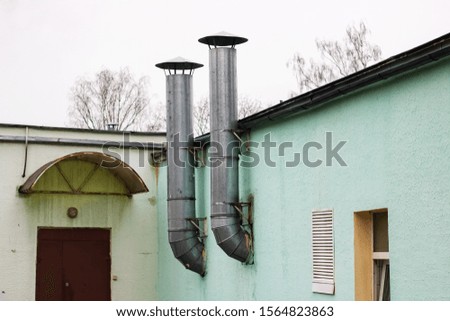 Two pipes on a green building at the door