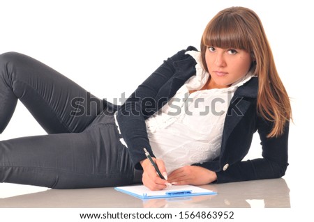 Beautiful caucasian white brunette woman lying holding pen and take a note in the notebook. Portrait on white background