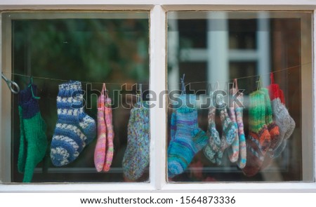 Baby knitted socks hanging in a shop. window frame on background. 
