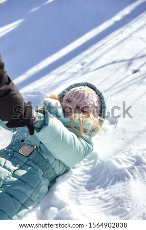 Happy woman and smiling little girl having fun in snow. Little kid girl in colorful clothes playing outdoors. Active leisure with child in winter on cold days. Happy child having fun with snow