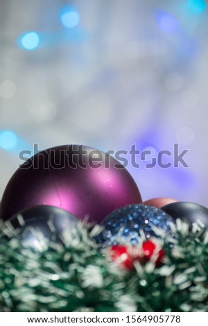 Christmas background with shiny colored toys.  Background with blurred lights garlands, blue and purple toys on one side of the picture. Copy space