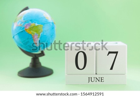 Close-up calendar of June 7 with blurred earth globe background