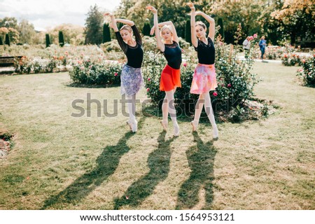 Three beautiful ballerinas girls dancing and balancing over sun light in summer park with beautiful background