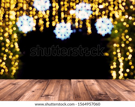 Wooden table top over abstract blurred background of light decoration and bokeh for Christmas holiday or festive party. Montage picture style to display the product.