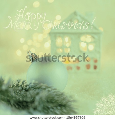 Greeting card Merry Christmas. Ball and Beautiful house or chalet and blurred background of winter decoration for the holiday. Toned image, bokeh, soft focus, closeup. Mockup, copy space.