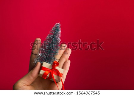 Funny fingers faces present gift box against red background with copy space for text. Happy family celebrating concept for Christmas or New Years day