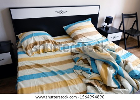 Striped sheets, pillows and duvet cover on the bed.  Color Bedding sheets and pillows striped textile in bedroom. Unmade Bed in the morning close up Royalty-Free Stock Photo #1564994890