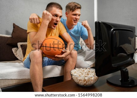 Teenagers watching basketball game on TV and cheering  