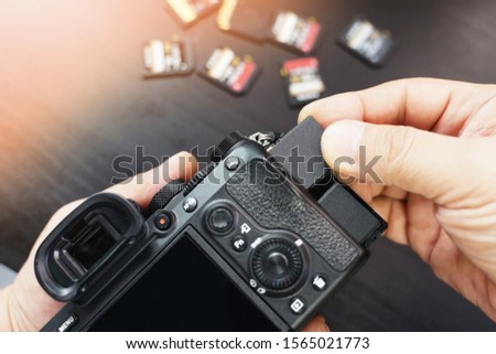 Photographer hand open the memory card slot cover and Insert memory card to camera slot at studio. selective focus                         