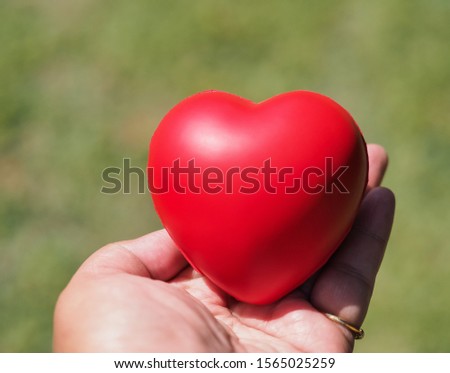 Close​ up​ red​ heart​ ball​ in​ hand​ with​ shadow​ with​ blurred​ of​ background​ for​ love​ concept