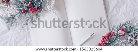 Christmas concept. White notebook with christmas decoration, wreath on a white background. Minimal winter vacation idea. Flat lay top view composition.