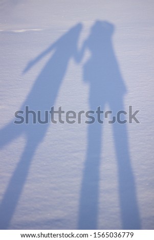 Holding hands creating a shadow in the snow. Shadows of people in the snow