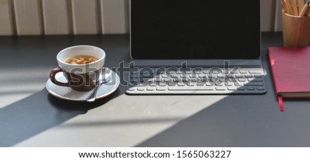Cropped shot of trendy workplace with tablet and office supplies with copy space and sunlight on the table