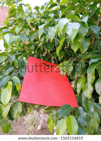 Non Woven ECO Friendly red color Bag on green leaves 