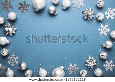 Merry Christmas and Happy Holidays greeting card, frame, banner. New Year. Noel. Christmas white, silver 
ornaments on blue background top view. Winter xmas holiday theme. Flat lay
