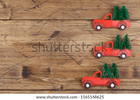 Small toy cars carring christmas tree on wood background . Seasonal holidays, greeting card, christmas mood concept. copy space close up