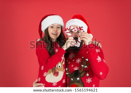 Christmas is like candy. Little child and father enjoy party. Small child and bearded man in festive mood. Happy family celebrate new year and xmas. Child and childhood. The child who loves christmas.