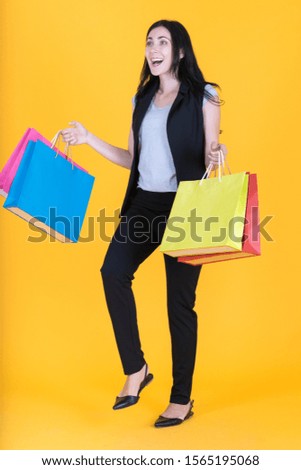 Portrait of happy businesswoman smiling in dark suit with shopping bag on yellow background using as professional modern business people and office concept.
