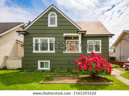Modest residential house with concrete pathway to the entrnace Royalty-Free Stock Photo #1565201626