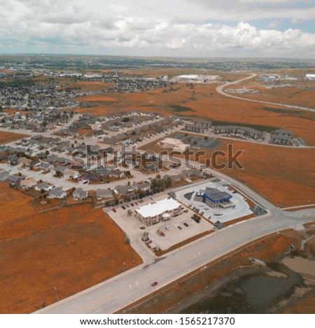 Panoramic aerial view of beautiful small town and surrounding area with meadows.