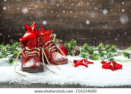 vintage christmas decoration red balls, stars and antique baby shoes on wooden background. retro style picture with snowflakes