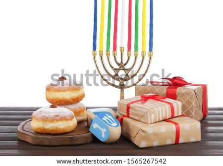 Menorah, gifts, donuts for Hanukkah and dreidel on table against white background