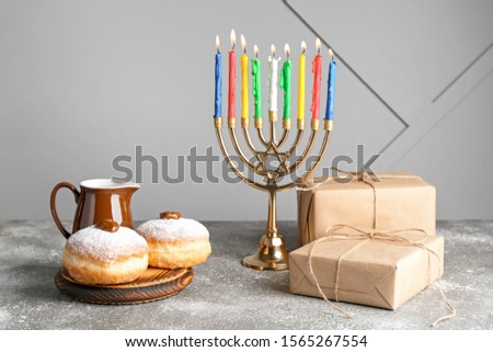 Menorah, donuts and gifts for Hanukkah on table