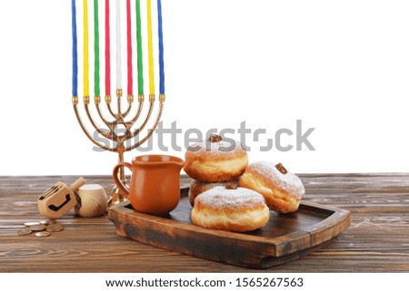 Menorah, donuts for Hanukkah and dreidels on table against white background