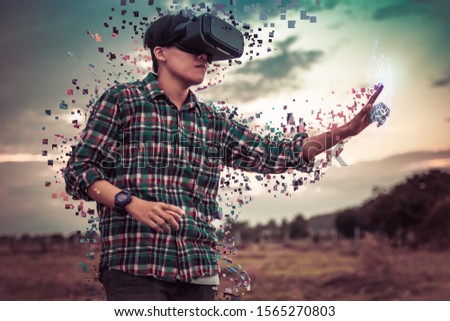 Asian man in tartan shirt wearing glasses of virtual reality dissolving into pixels on outdoor. Future Technology Concept