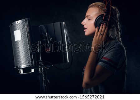 Charming cool student is singing her new song at recording studio.
